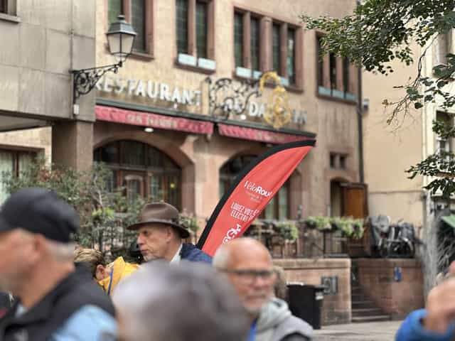VéloRouge-Fahne und Gäste einer Stadtführung vor einem elsässischen Restaurant
